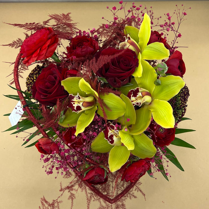 Struttura bouquet a cuore con rose rosse, ranuncoli e orchidee