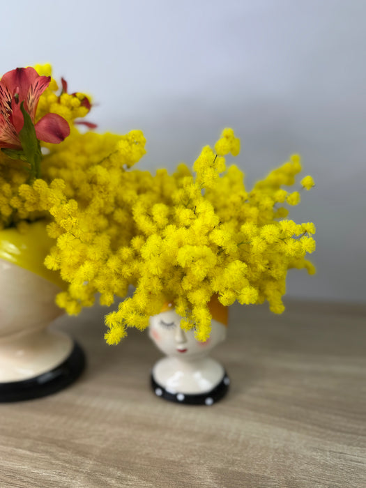 White ceramic head vase with mimosa and various flowers